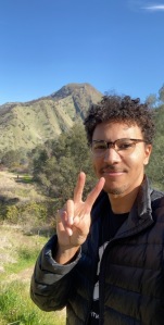 Tyus Williams giving the peace sign with a mountain behind him. Photo provided by Tyus Williams